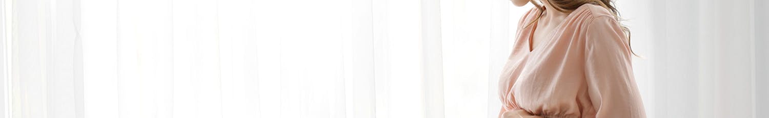 Foto av ung gravid kvinna framför fönster